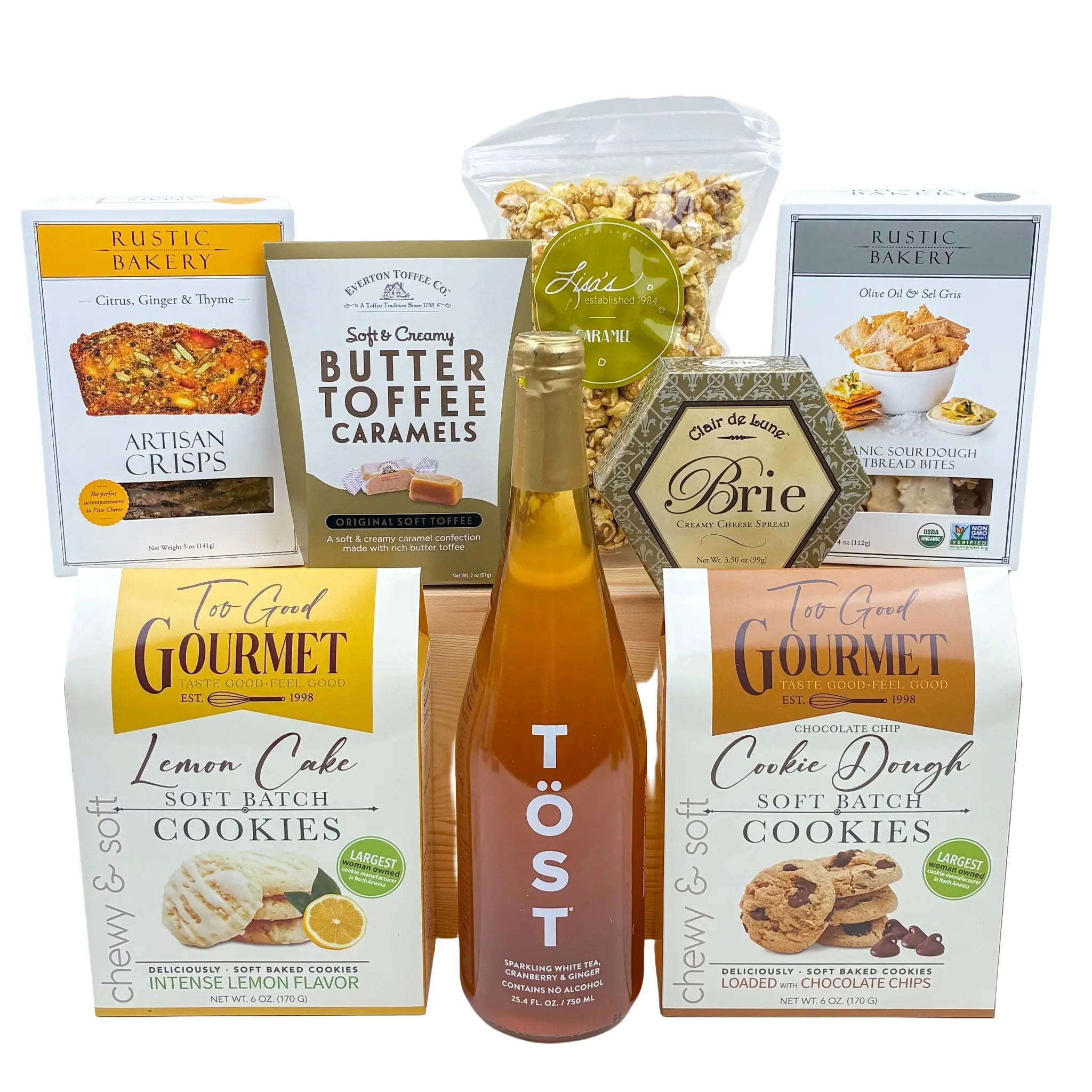 Assorted gourmet food items including cookies, caramels, and a bottle of Töst on a white background