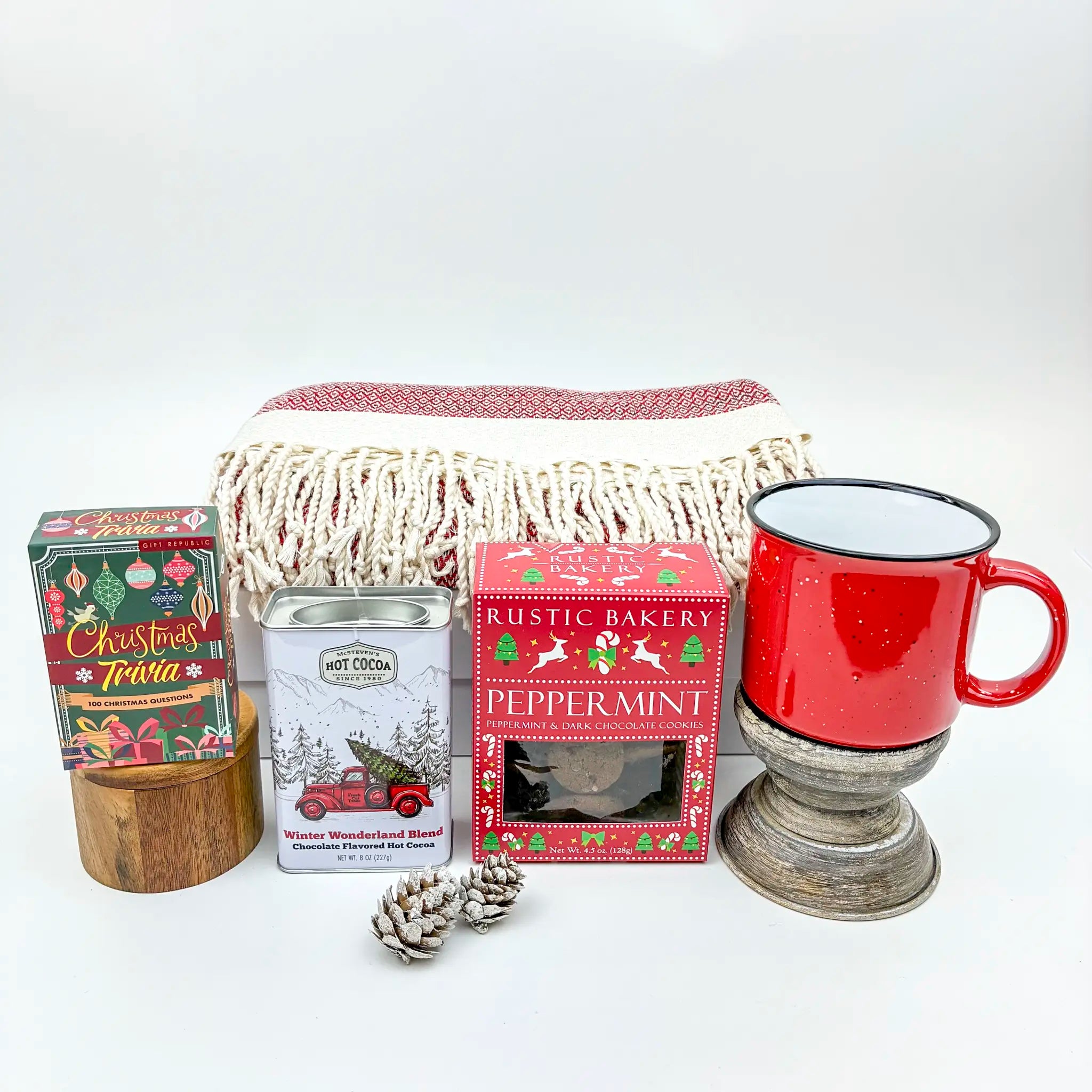 Holiday-themed gift set with a red mug, tea bags, and a blanket on a white background