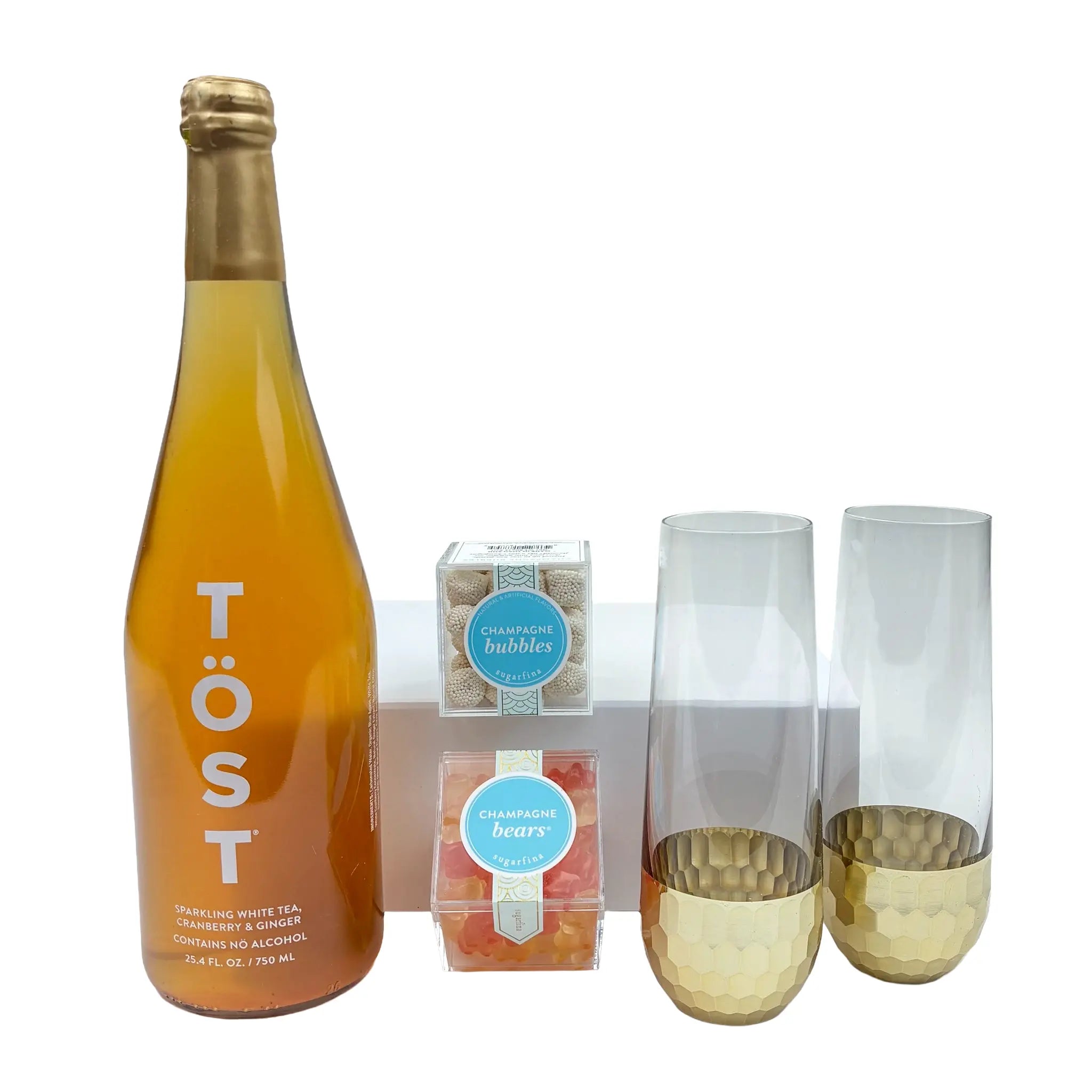 Bottle of Töst sparkling white tea, two glasses with gold bases, and a small box on a white background