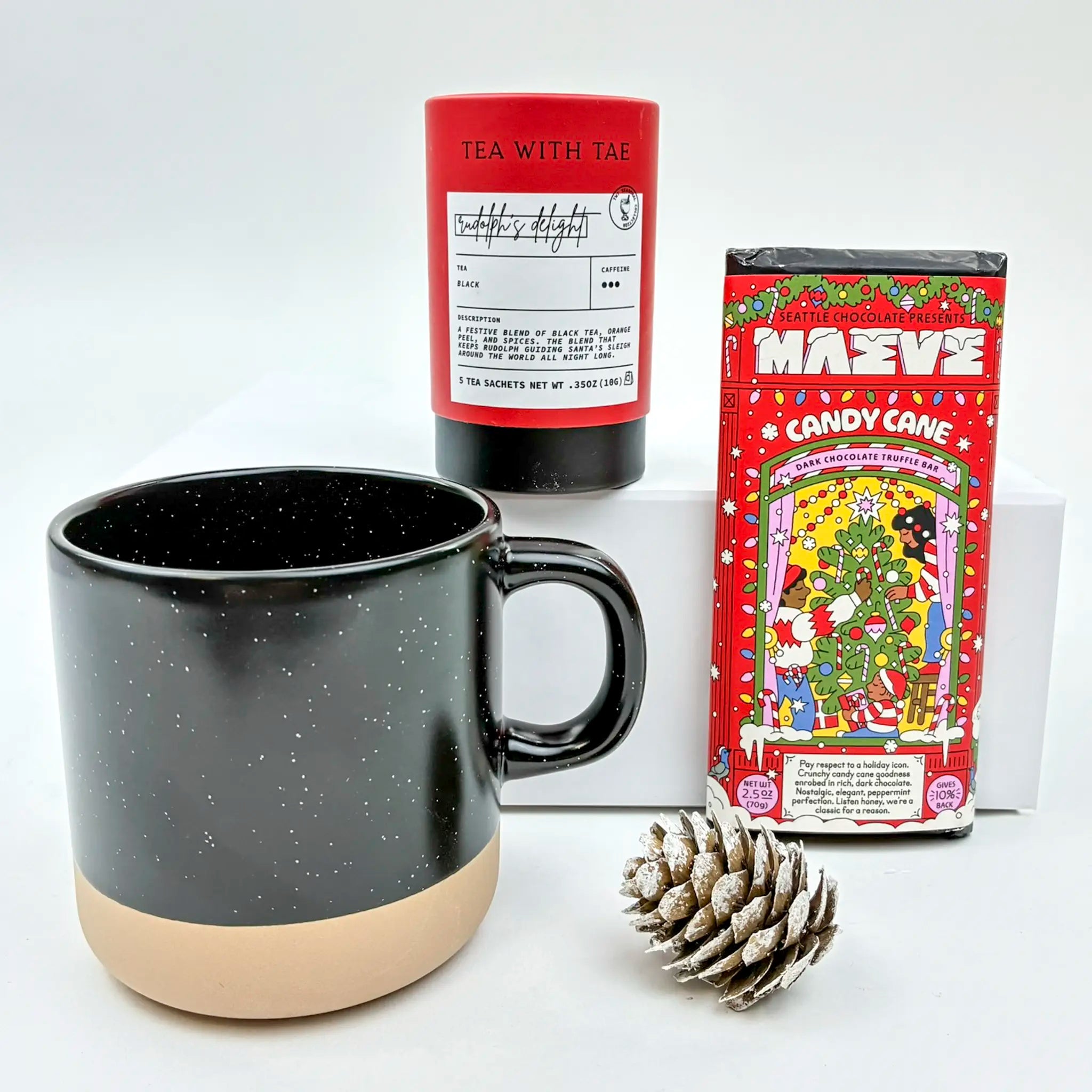 Black mug with beige base, red tea canister, and candy cane-themed box on a white background