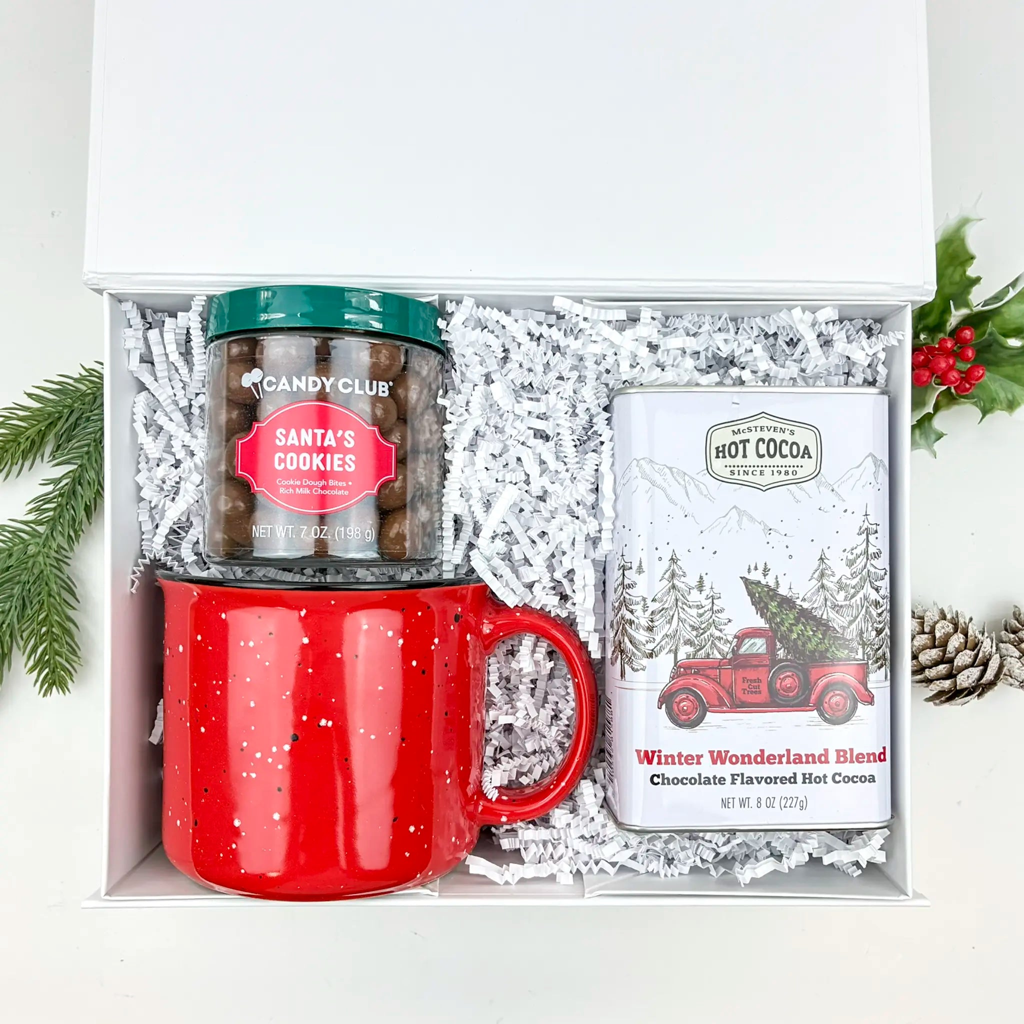 Gift set with red mug, hot cocoa mix, and candy jar in a decorative box.