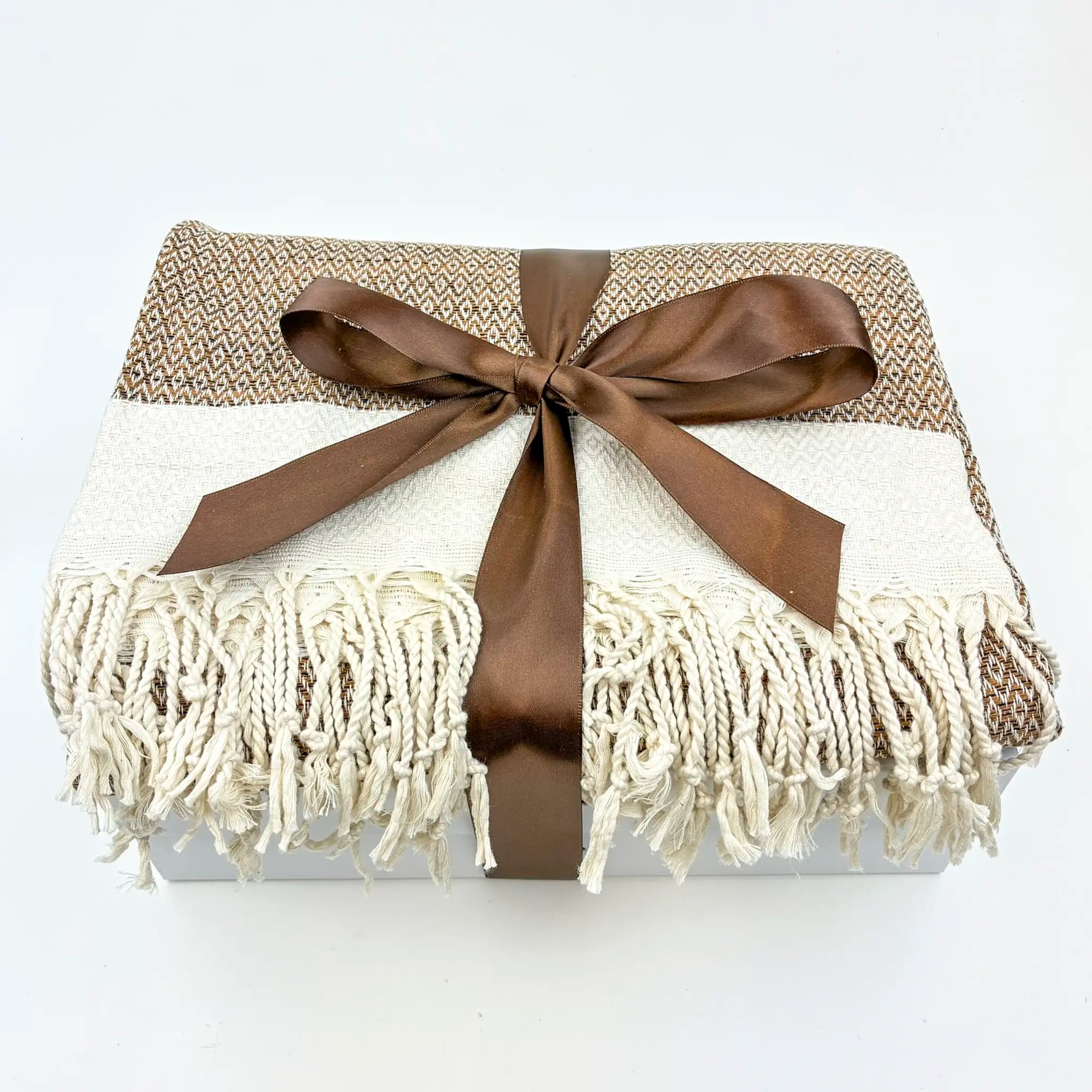 Blanket with brown ribbon and fringes on a white background