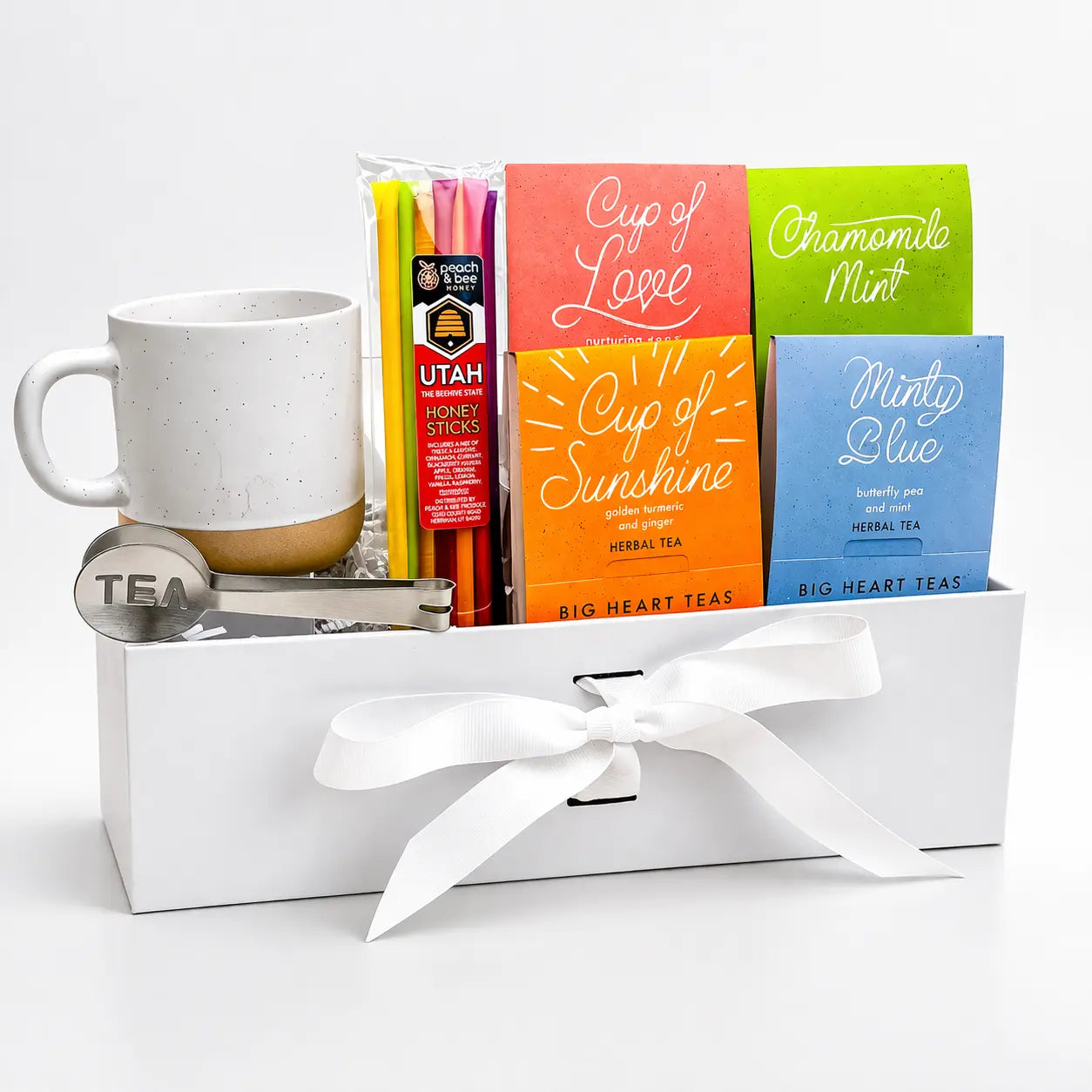 Tea gift set with mug, tea bags, and honey sticks in a white box on a light gray background