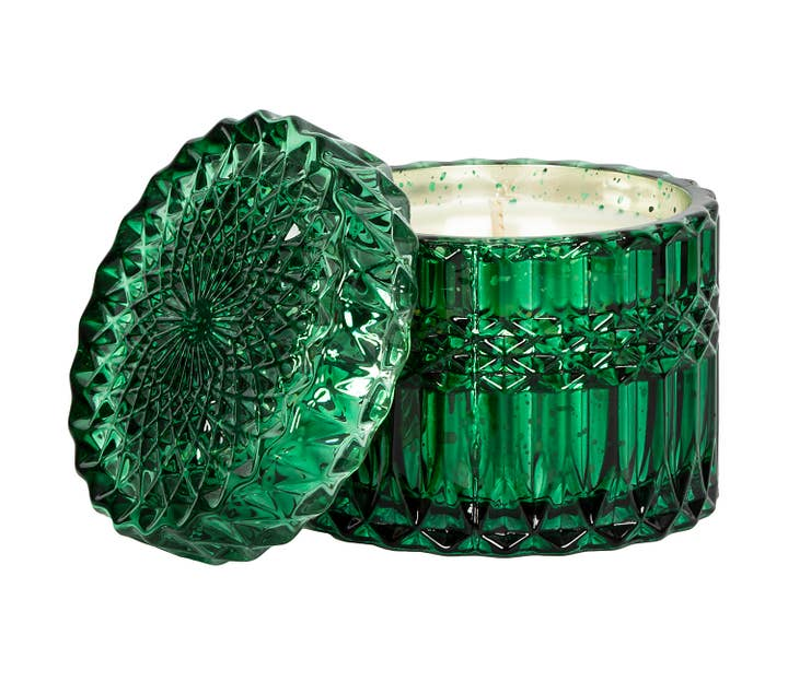 Green glass candle with textured design on a white background