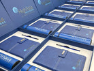 Collection of blue branded portfolios and pens in display boxes with 'High Falls Advisors' branding.