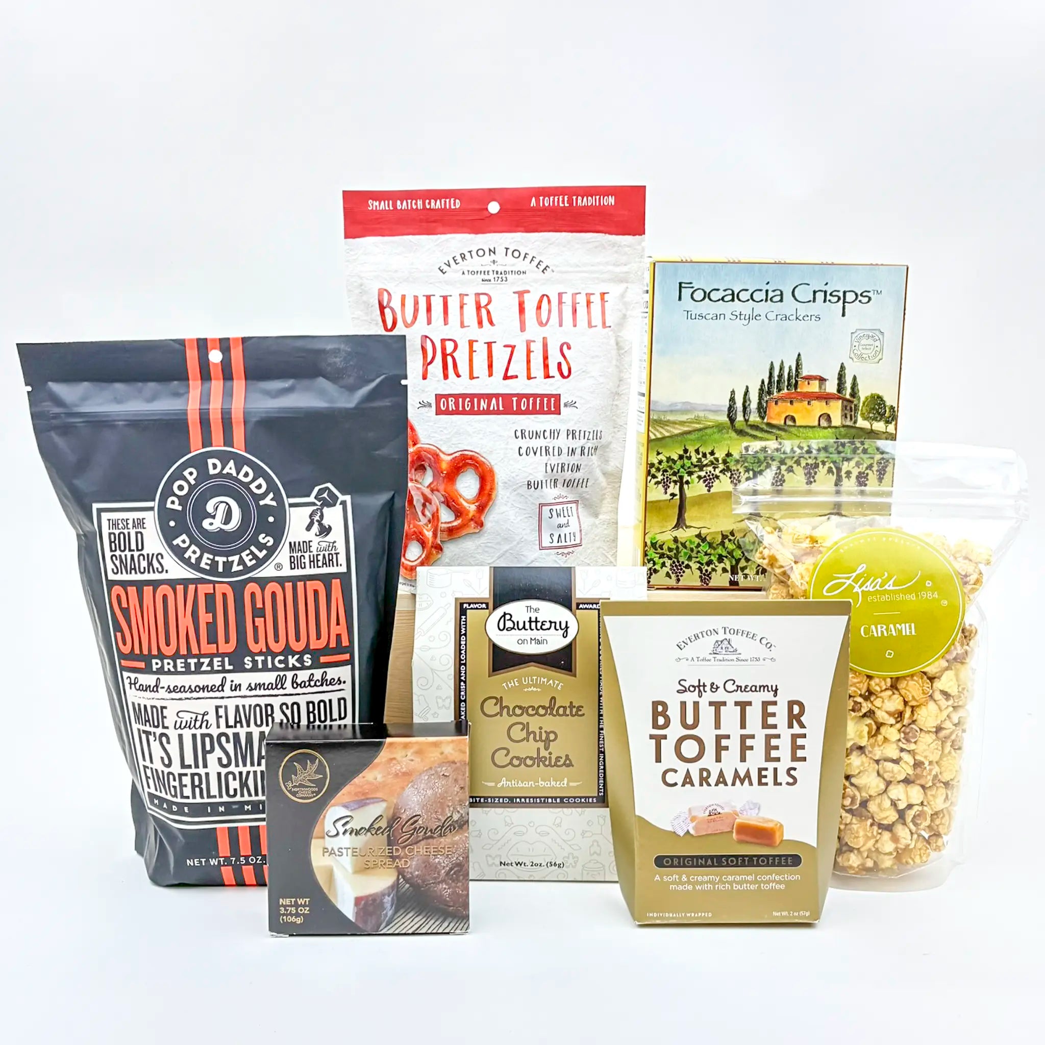 Assorted snack packages including smoked gouda pretzel sticks, butter toffee pretzels, and caramels on a white background