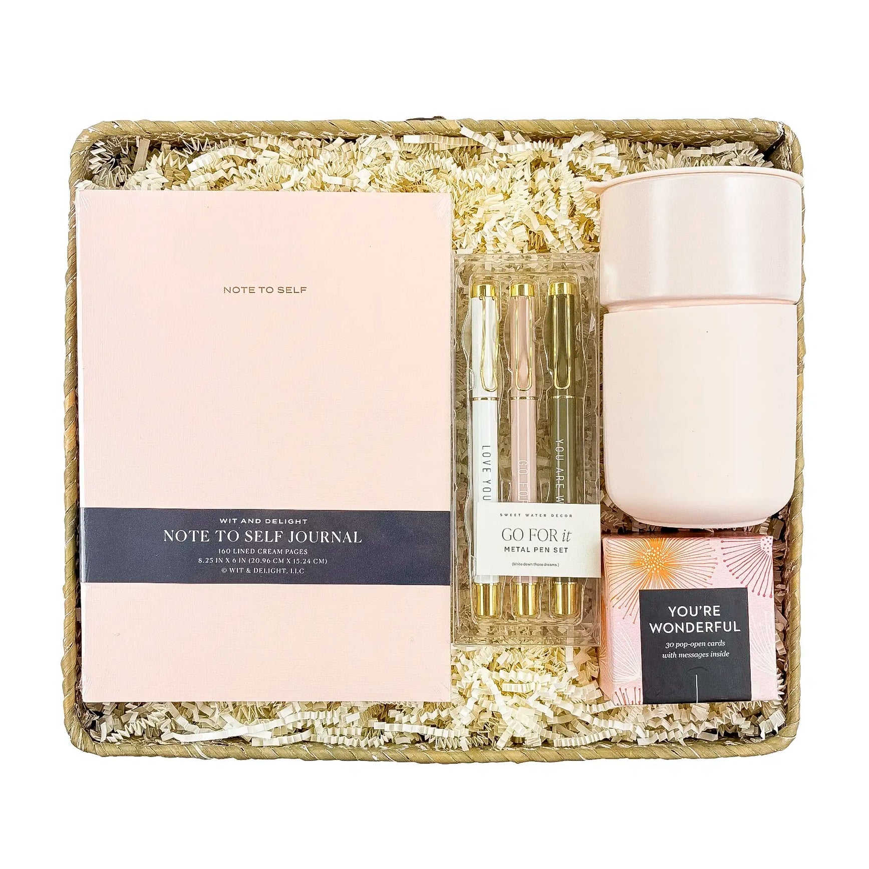 Gift set with a journal, candle, and small bottle on a white background
