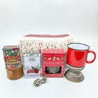 Holiday-themed gift set with a red mug, tea bags, and a blanket on a white background