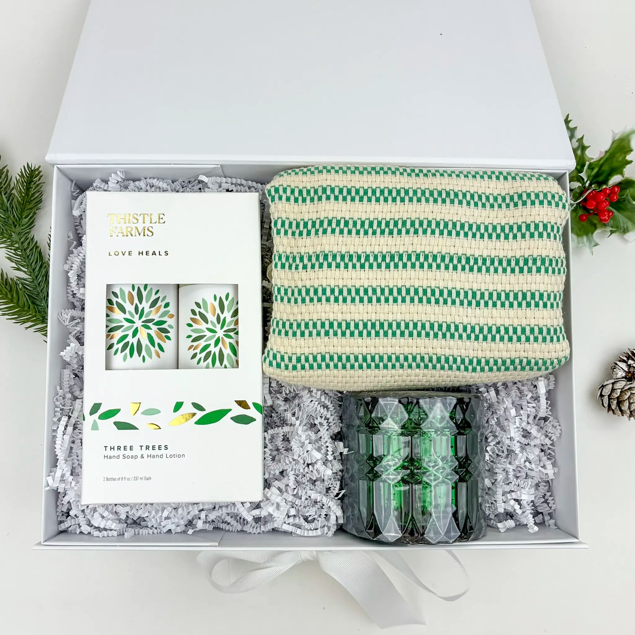 Gift set with a striped bag, candles, and a box labeled 'Three Trees' on a white background.