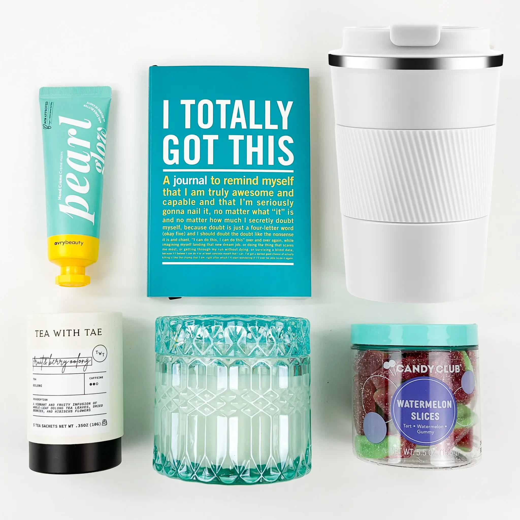 Collection of items including a journal, travel mug, and candy on a white background