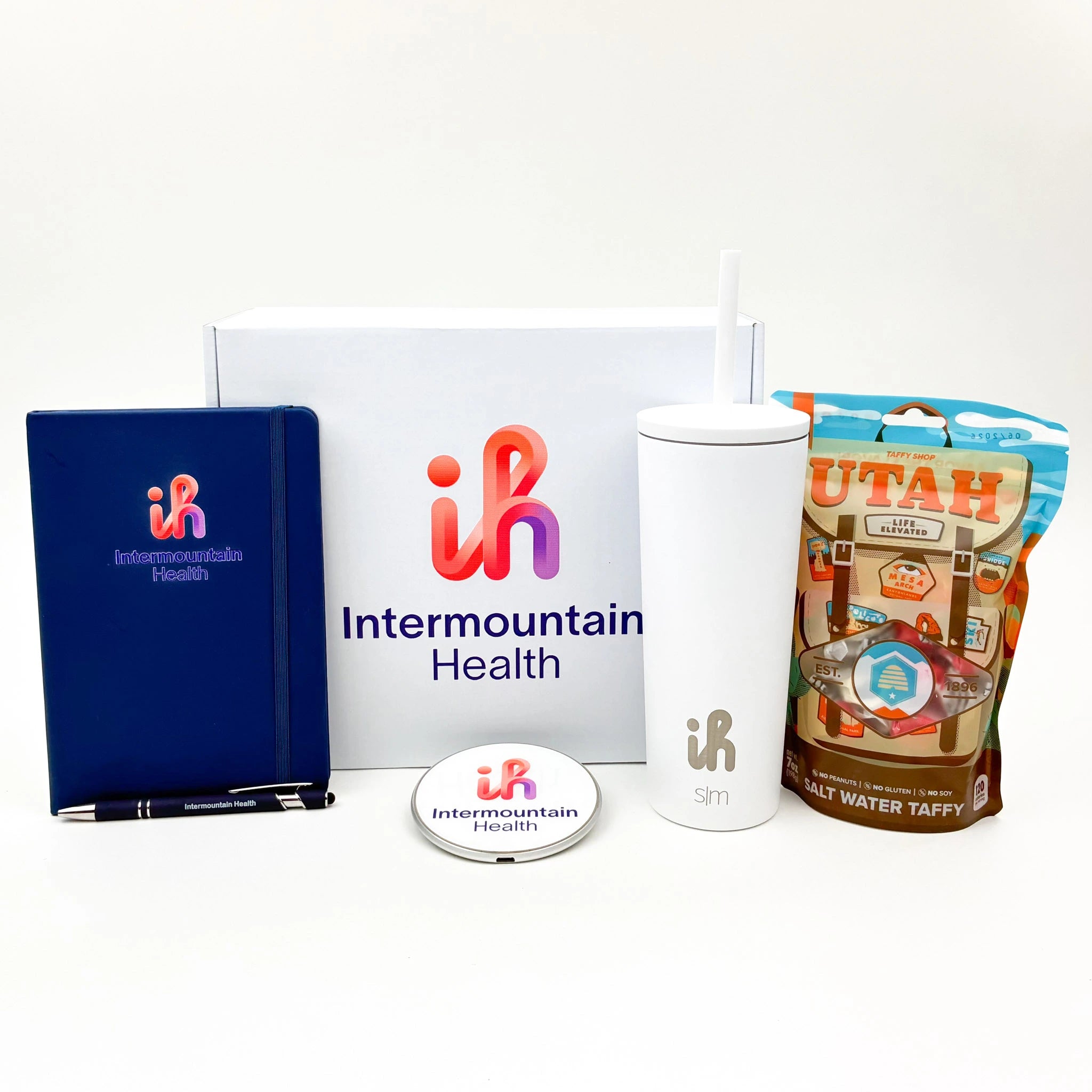 Collection of Intermountain Health branded items including a notebook, tumbler, and candy on a white background.