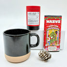 Black mug with beige base, red tea canister, and candy cane-themed box on a white background