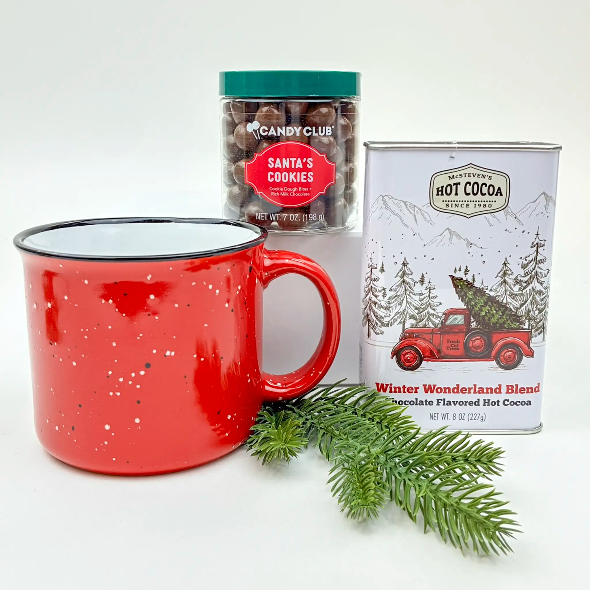 Red mug with a can of hot cocoa and a container of cookies on a white background