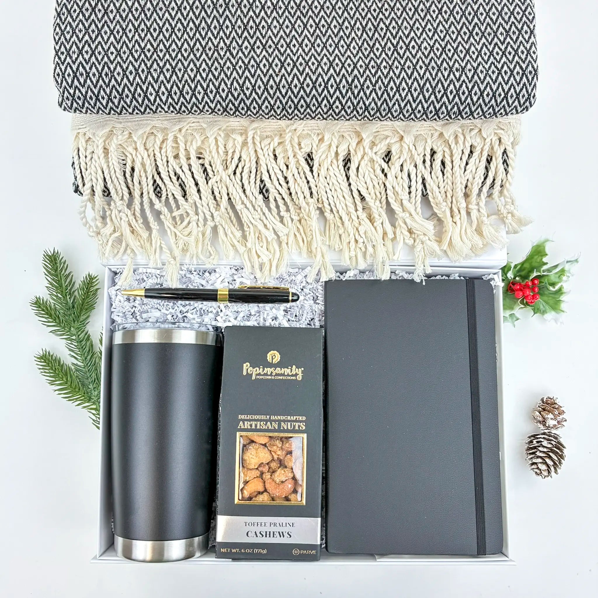 Gift set with a notebook, tumbler, and snacks on a white background
