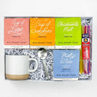 Tea gift set with tea boxes, mug, spoon, and honey sticks in a box.