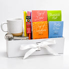 Tea gift set with mug, tea bags, and honey sticks in a white box on a light gray background