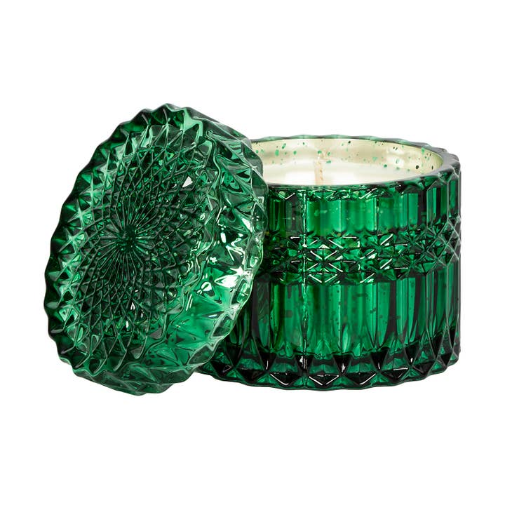 Green glass candle with textured design on a white background